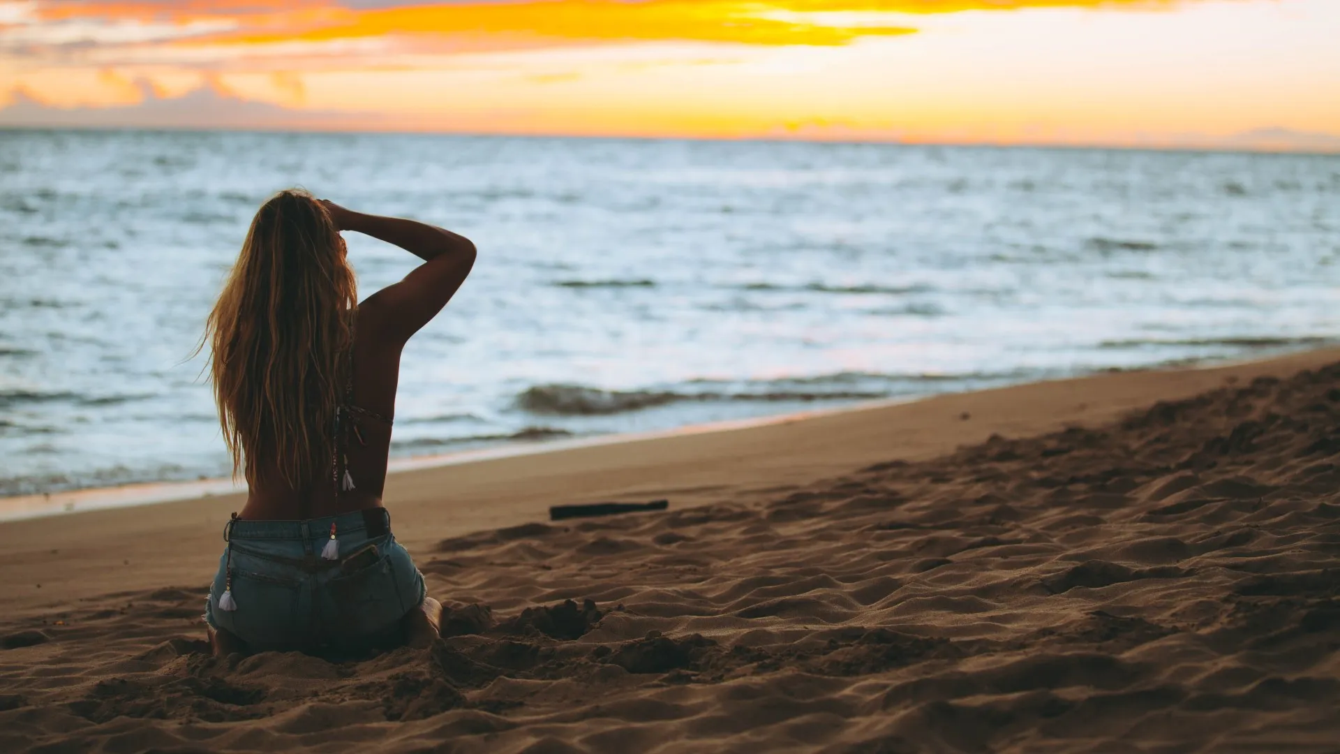 Turquoise water and a palm-lined Hawaiian beach at sunset.