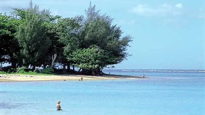 A swimmer wading in the shallow, reef-protected water at Anini Beach on Kauai’s North Shore.