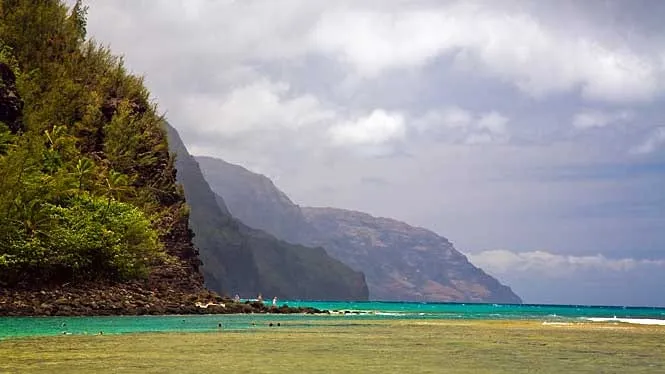 The Na Pali cliffs rising beyond the calm reef water at Haena Beach Park.