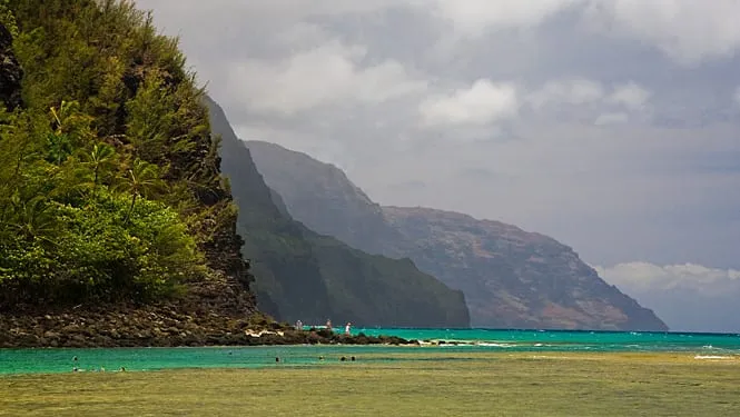 Ke’e Beach’s reef lagoon with the Na Pali cliffs rising behind it at Haena.