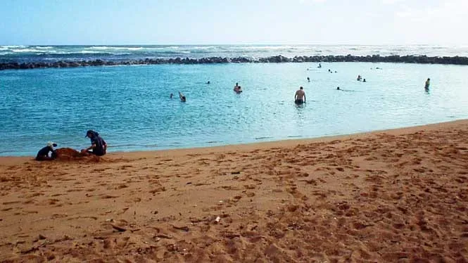 Swimmers in the rock-walled ocean pool at Lydgate Beach Park, Wailua.