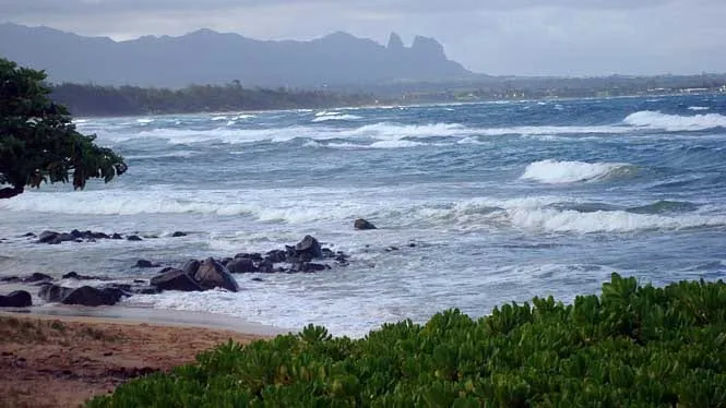 Rough surf at Nukolii Beach Park, with the Sleeping Giant ridge in the distance.