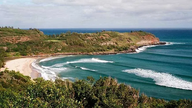 The sandy cove of Rock Quarry (Kahili) Beach between green headlands near Kilauea.