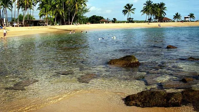 Families wading in the shallow, rock-sheltered water at Salt Pond Beach Park, Hanapepe.