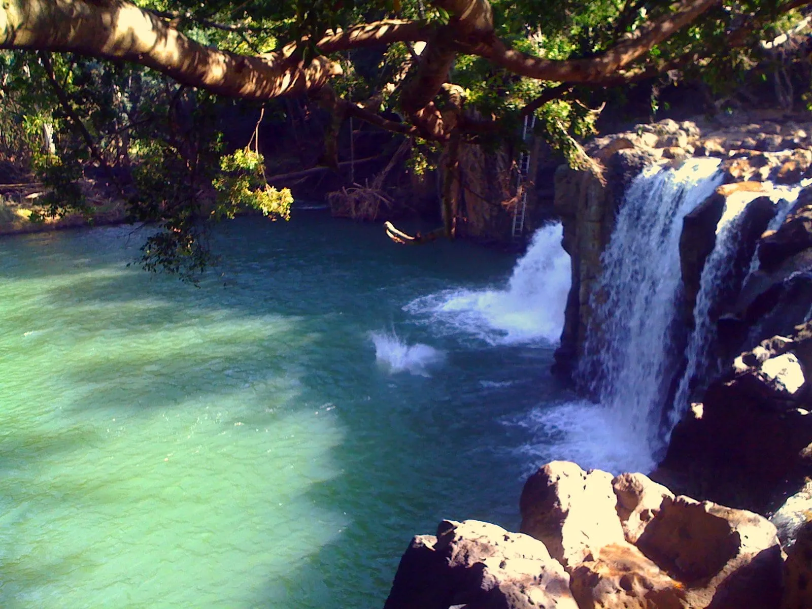 Kipu Falls pouring into its green swimming hole on Kauai.