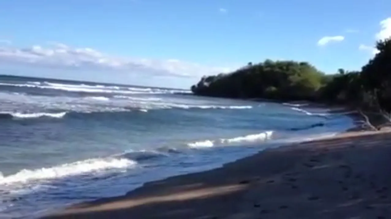 The small curve of Lopa Beach with a wooded point at its end, on Lanai’s east shore.