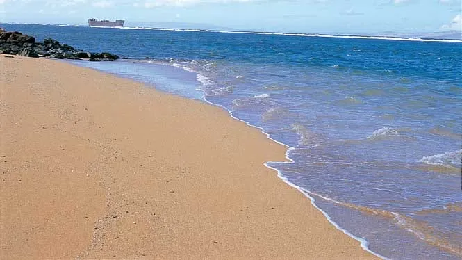 Gentle surf on the sand at Shipwreck (Kaiolohia) Beach, Lanai, with the wreck far offshore.