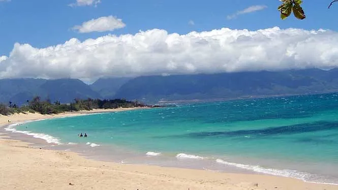 The long sand of Baldwin Beach Park with the West Maui Mountains across the bay.