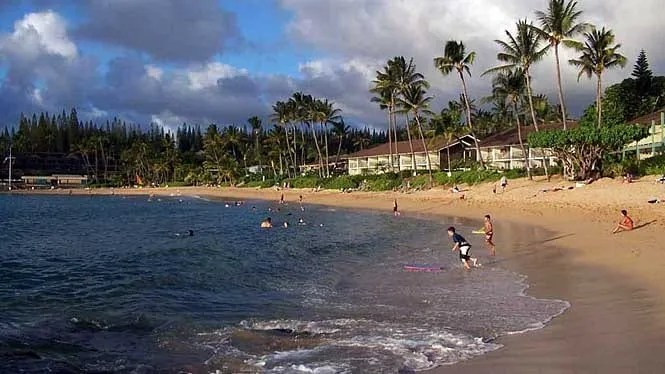 Napili Bay’s crescent of sand with swimmers in the shallows and low-rise condos behind.