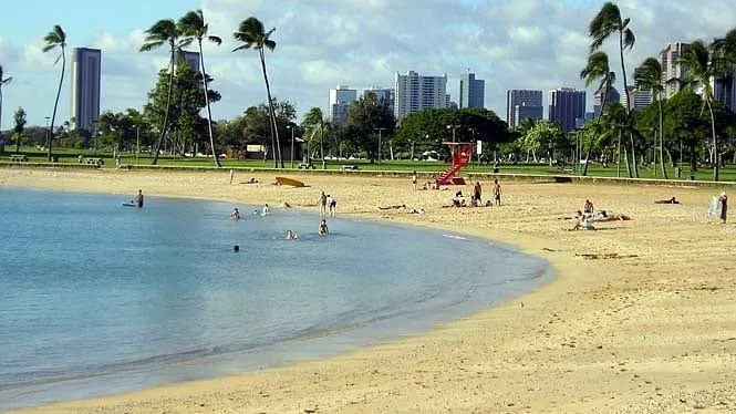 Swimmers in the calm lagoon at Ala Moana Beach Park, with the Honolulu skyline behind.