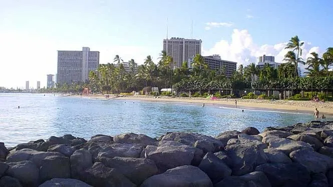 The rock groin and calm water at Fort DeRussy Beach, with the Hilton Hawaiian Village behind.