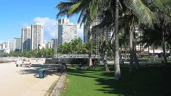 Kuhio Beach Park’s sand and lawn below the Waikiki hotels.