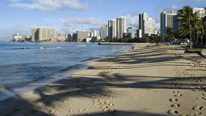 Footprints on the sand at Waikiki Beach, looking along the shore toward the hotels.
