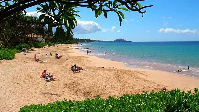 Sunbathers on the golden sand of Wailea Beach, with Kahoolawe faint on the horizon.
